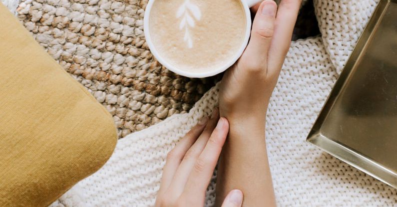 Taste Coffee - Top view crop unrecognizable female resting hands with cup of freshly brewed cappuccino on cozy soft cloth