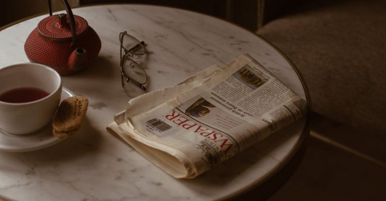 Brew Method - From above of round marble textured table with tea set placed near newspaper and eyeglasses in retro style cafe