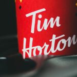 Aroma Ride - Hot coffee in red paper cup with black lid placed in car drink holder on blurred background