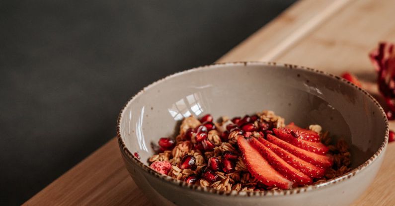 Taste Judgment - A bowl of strawberries and granola on a wooden cutting board
