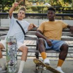 Culture Hangout - Young men sitting on bench with skateboards in park
